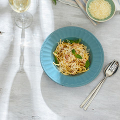 Plate spaghetti carbonara with white wine on white wooden table close up, top view. Dinner table
