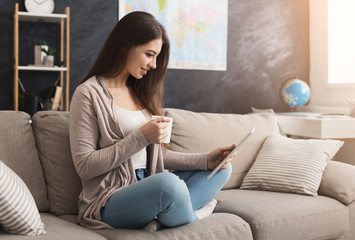 Girl reading on digital tablet and drinking coffee