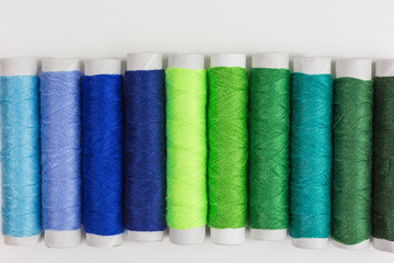 spools and bobbins of sewing thread in shades of blue and green