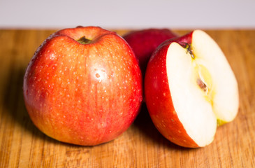 Three red apples with shadow on a wooden board