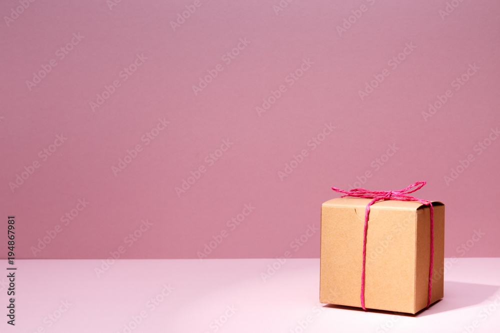 Wall mural Craft cardboard gift box on the solid pink background. Holiday and gift concept