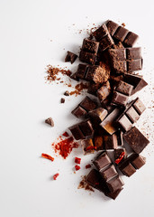 Chunks of dark chocolate with spices on white background.