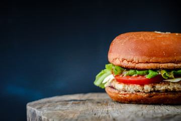 Appetizing homemade burger on a wooden table on dark blue background