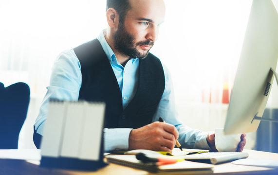 Bearded young businessman working on modern office. Consultant man thinking looking in monitor computer. Manager typing on keyboard in coworking workplace, startup project concept