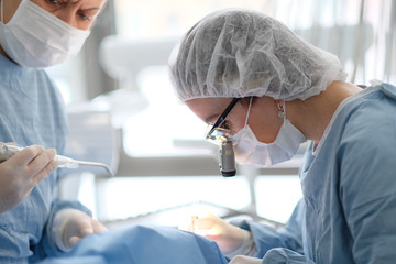 Doctor with an assistant in the surgical dental surgery in the clinic