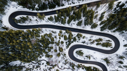Winding road from high mountain pass, in winter time. Aerial view by drone . Romania	