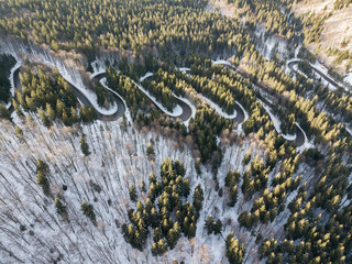 Winding road from high mountain pass, in winter time. Aerial view by drone . Romania	