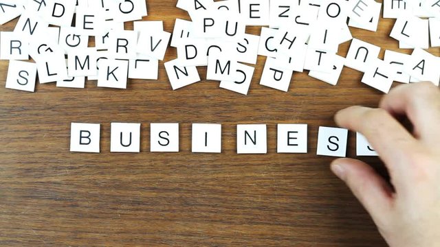 "Business" writing with plastic letters on a wooden table. Conceptual Time Lapse video.