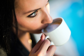 Portrait of beautiful young woman sitting at a table with a cup of coffee
