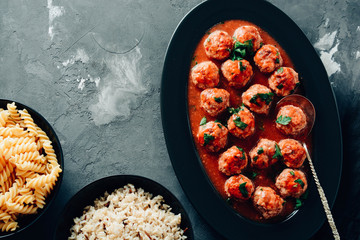 Meatballs in a spicy tomato sauce with fresh aromatic herbs. Rice and pasta.