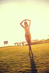 happy beautiful woman in bikini on the green grass on sunset.