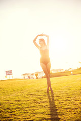 happy beautiful woman in bikini on the green grass on sunset.