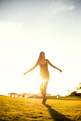 happy beautiful woman in bikini on the green grass on sunset.