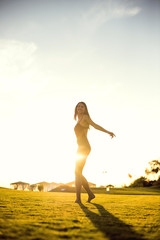 happy beautiful woman in bikini on the green grass on sunset.