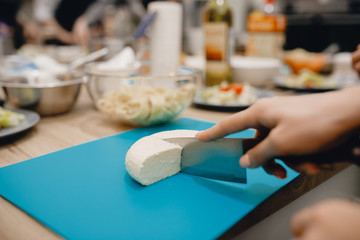 Obraz na płótnie Canvas Close-up of a girl cuts a sharp cheese knife.