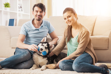 Young couple are playing with their puppy dog Husky