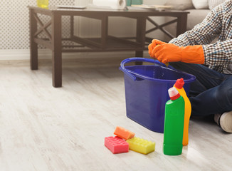 Unrecognizable man cleaning home with detergents