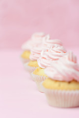 Cupcake decorated with pink buttercream on pastel pink background. Sweet beautiful cake. Vertical banner, greeting card for birthday, wedding, women's day. Close up photography. Selective focus
