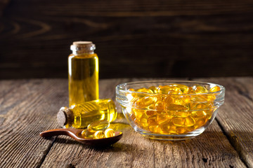 Fish oil capsules on wooden background, vitamin D supplement