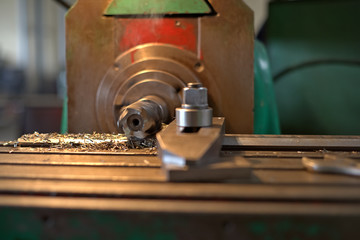 The detail is clamped by clips on a table. Dry boring by a trailer mill with a smoke and steam. The look with a side, the worker operates manufacturing process at plant.