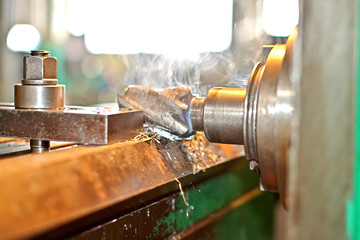 The detail is clamped by clips on a table. Dry boring by a trailer mill with a smoke and steam. The look with a side, the worker operates manufacturing process at plant.