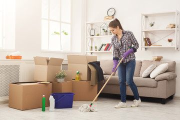 Young woman cleaning home with mop
