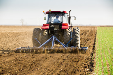 Farmer in tractor preparing land with seedbed cultivator as part of pre seeding activities in early...