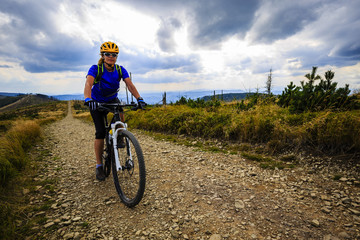 Fototapeta na wymiar Mountain biking women riding on bike in summer mountains forest landscape. Woman cycling MTB flow trail track. Outdoor sport activity.