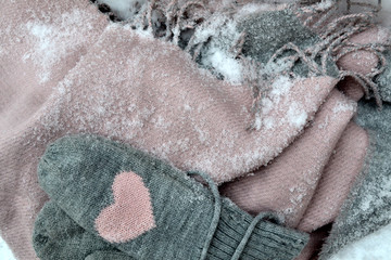 Winter woolen textile. Scarf and mittens on the snow. Beautiful winter background. Cold season.