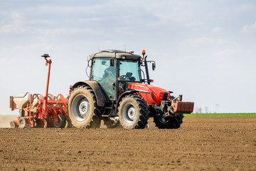 Obraz premium Farmer seeding, sowing crops at field. Sowing is the process of planting seeds in the ground as part of the early spring time agricultural activities.