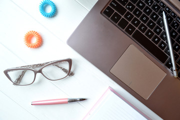 Beautiful female workplace. Laptop and bright accessories on the white wooden desk.
