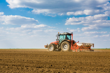 Fototapeta na wymiar Farmer seeding, sowing crops at field. Sowing is the process of planting seeds in the ground as part of the early spring time agricultural activities.