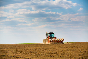 Obraz premium Farmer seeding, sowing crops at field. Sowing is the process of planting seeds in the ground as part of the early spring time agricultural activities.