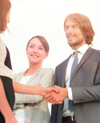 Businesspeople  shaking hands against room with large window loo