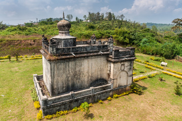 Madikeri, India - October 31, 2013: Closeup on small white and gray Guru Rudrappa mausoleum with bull statue on top, set in green garden of domain Raja Tombs. Shot form roof.