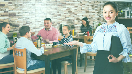 Smiling waitress holding tray with dishes meeting guests