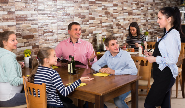 Parents with children are giving order to cheerful waitress