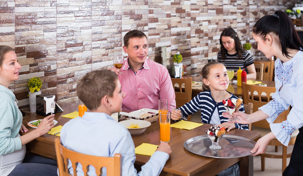 professional brunette waitress serving family in family cafe