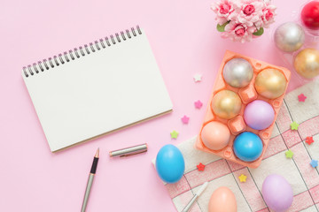 Flat lay top view colorful easter egg painted in pastel colors composition and mock up blank notebook with paint brush on pink pastel color background. Easter day background top view with copy space.