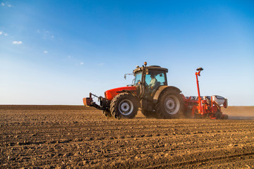 Farmer seeding, sowing crops at field. Sowing is the process of planting seeds in the ground as part of the early spring time agricultural activities.