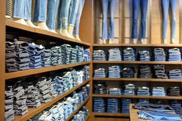 Different neatly folded jeans on the shelves of the store in the Mall