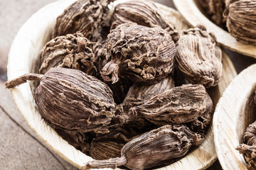 Whole black cardamom in a bowl on wooden background