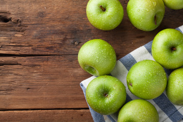 Ripe green apples in a wooden bowl on an old rustic table. Useful fruits on wooden background. Top view with copy space