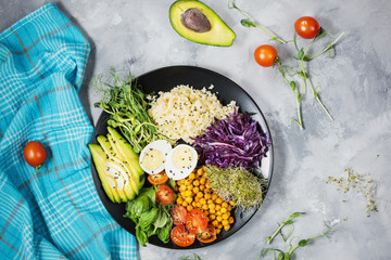 Healthy vegan lunch bowl. Vegan buddha bowl. Vegetables and nuts in buddha bowl on concrete background. Top view.