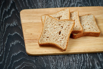 Sliced bread on wooden cutting Board, on dark wooden background, bran