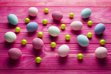 Colored Easter eggs and green balls on pink wooden background