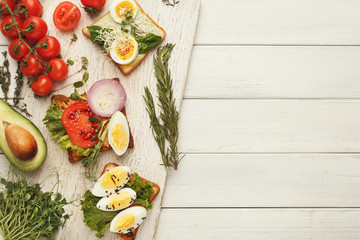 Variety of healthy vegetarian sandwiches on white wood, top view