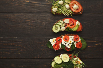 Variety of healthy vegetarian sandwiches on dark wood, top view