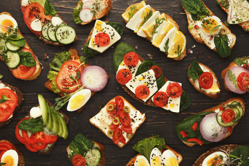 Variety of healthy vegetarian sandwiches on dark wood, top view