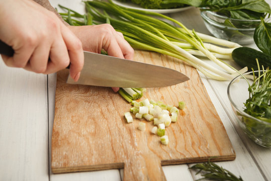 Woman cutting spring onion for salad